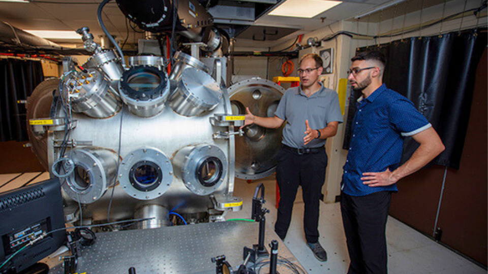 two men standing next to object in lab