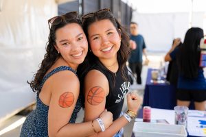 Two students smile with basketballs painted on their arms