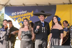 Mariachi performers on stage with the UC Irvine Homecoming Block Party logo in the background